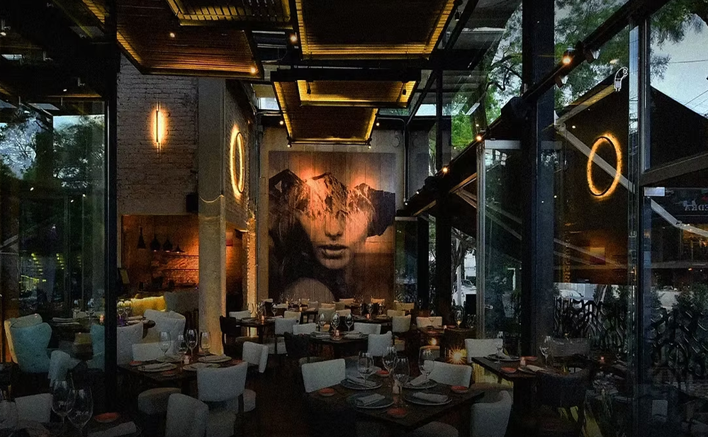 Restaurante elegante en Polanco, Ciudad de México, con iluminación ambiental cálida, grandes ventanales, decoración contemporánea y ambiente sofisticado para cenas exclusivas.