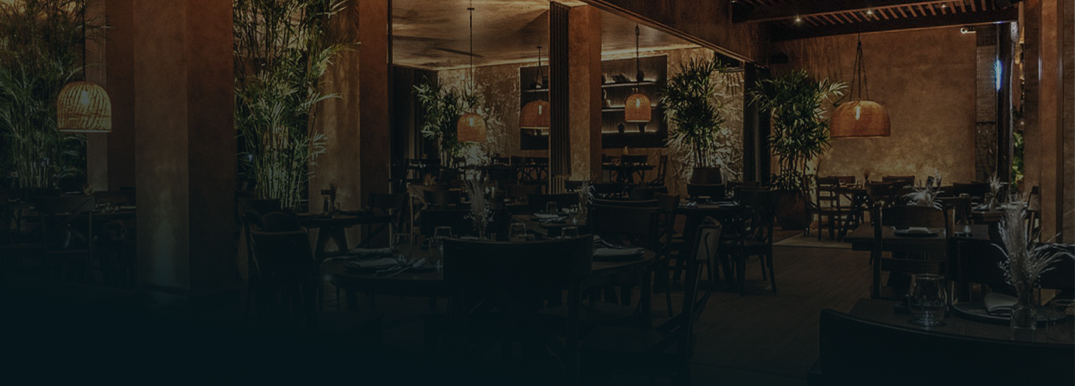 Restaurante elegante en Polanco, CDMX, con iluminación cálida, decoración sofisticada en madera y ambiente íntimo rodeado de vegetación interior.